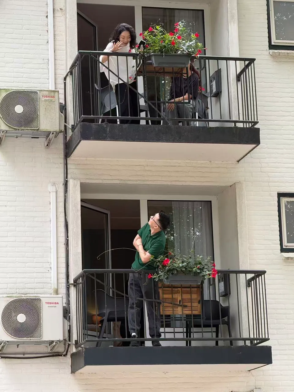 Friends greeting each other across the hotel balconies.