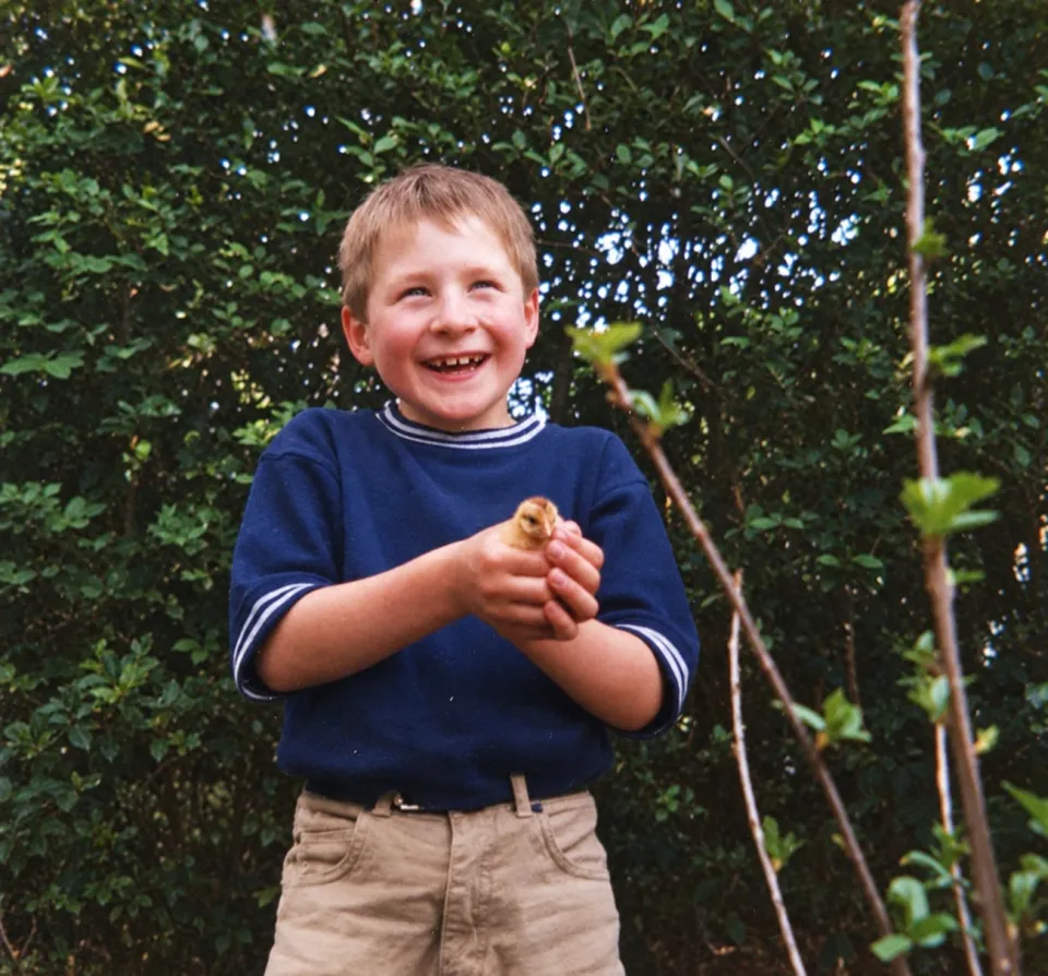 Kees as a child, holding a small bird outdoors.