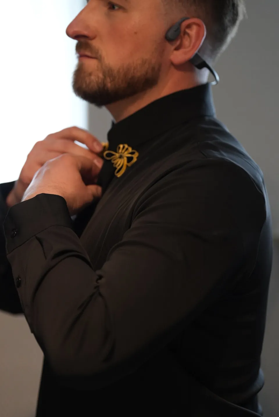 Kees adjusting the collar of his black embroidered wedding outfit.