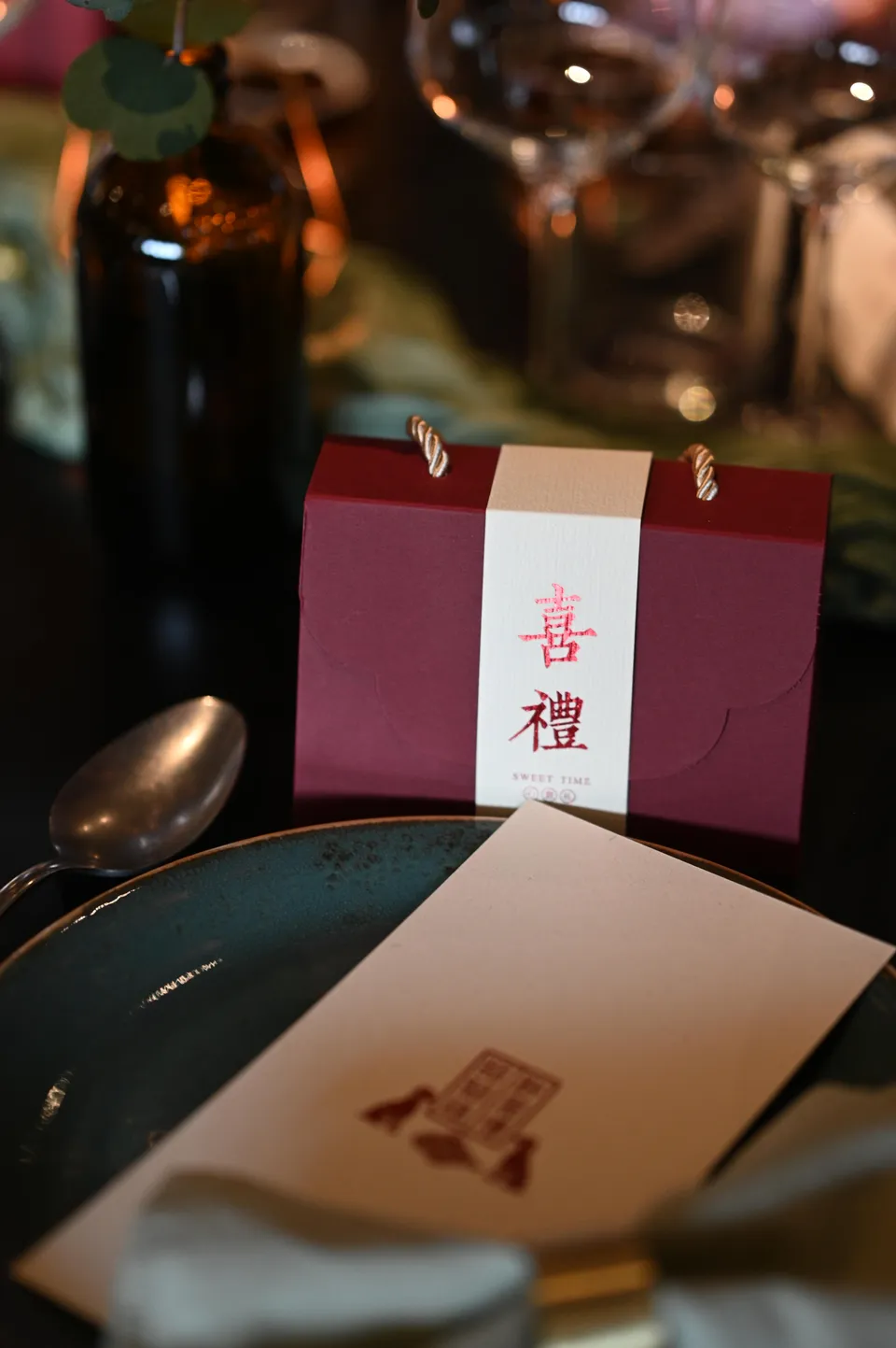 The burgundy favour box beside the wedding stationery.
