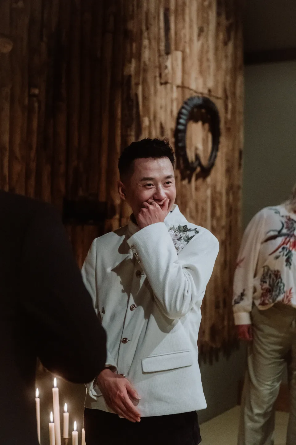 Ricky smiling with his hand near his face as he listens to Kees’s vows.