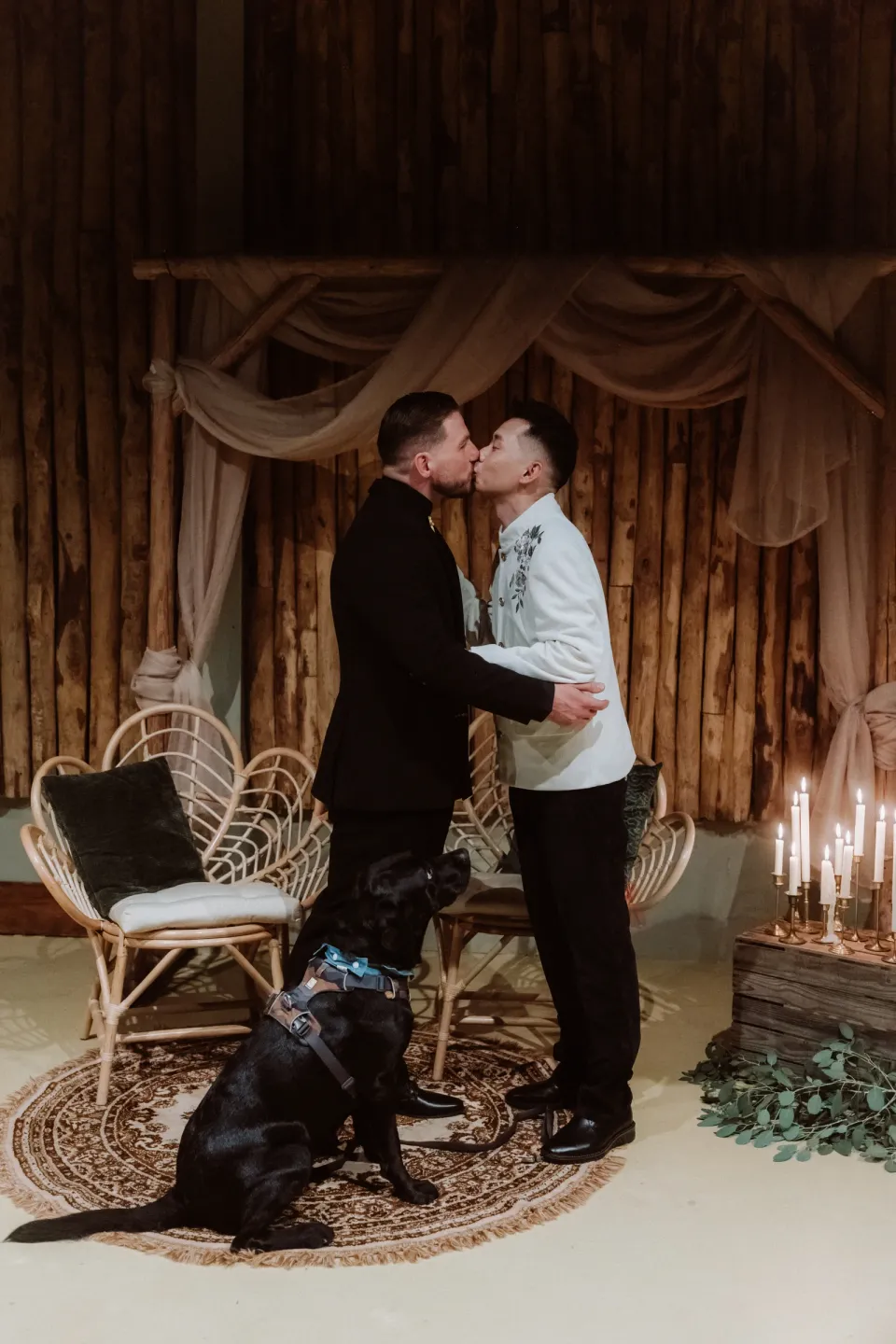Ricky and Kees kissing in the candlelit ceremony room, with the dogs at their feet.