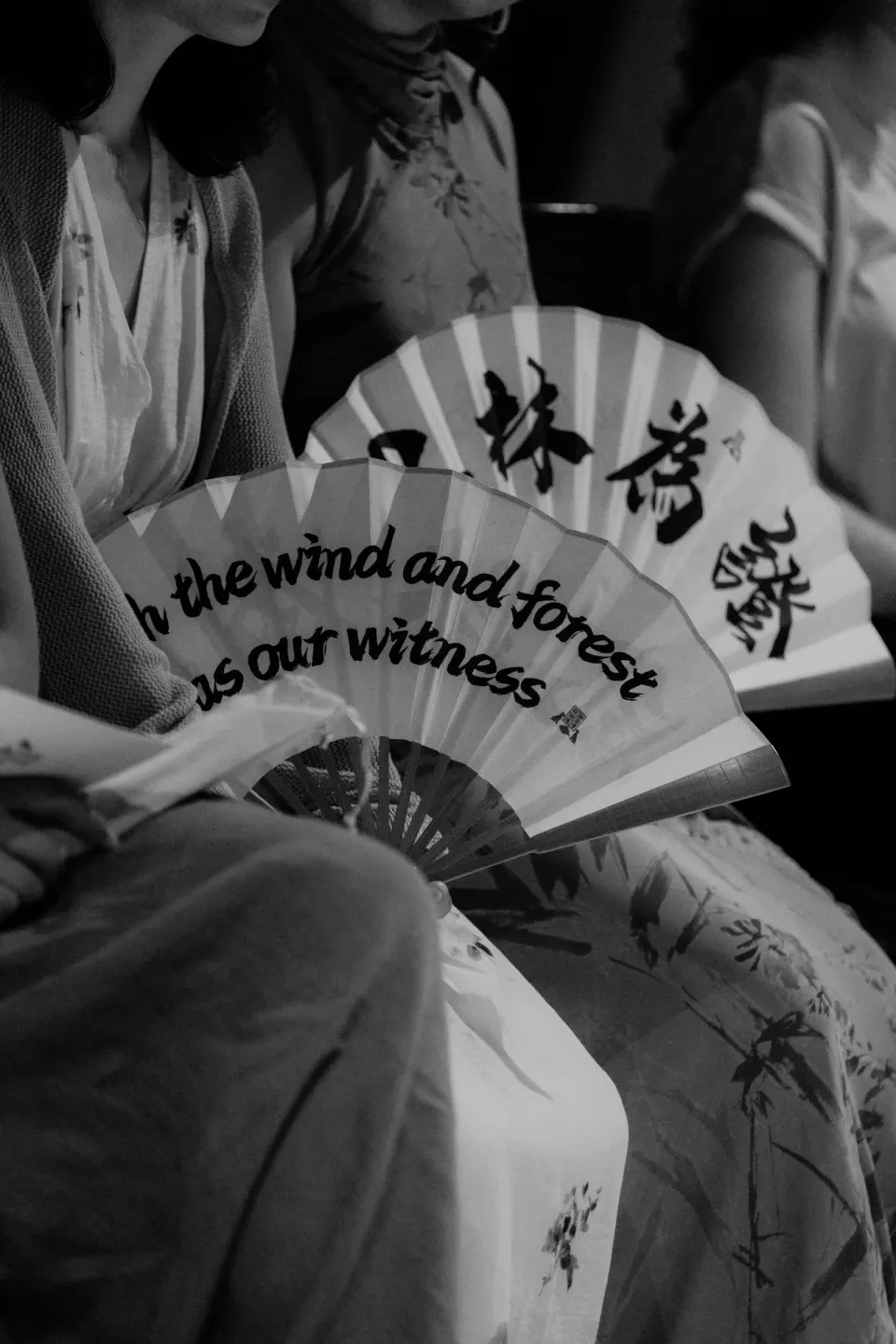 A guest holding the custom folding fan with the wind-and-forest theme.
