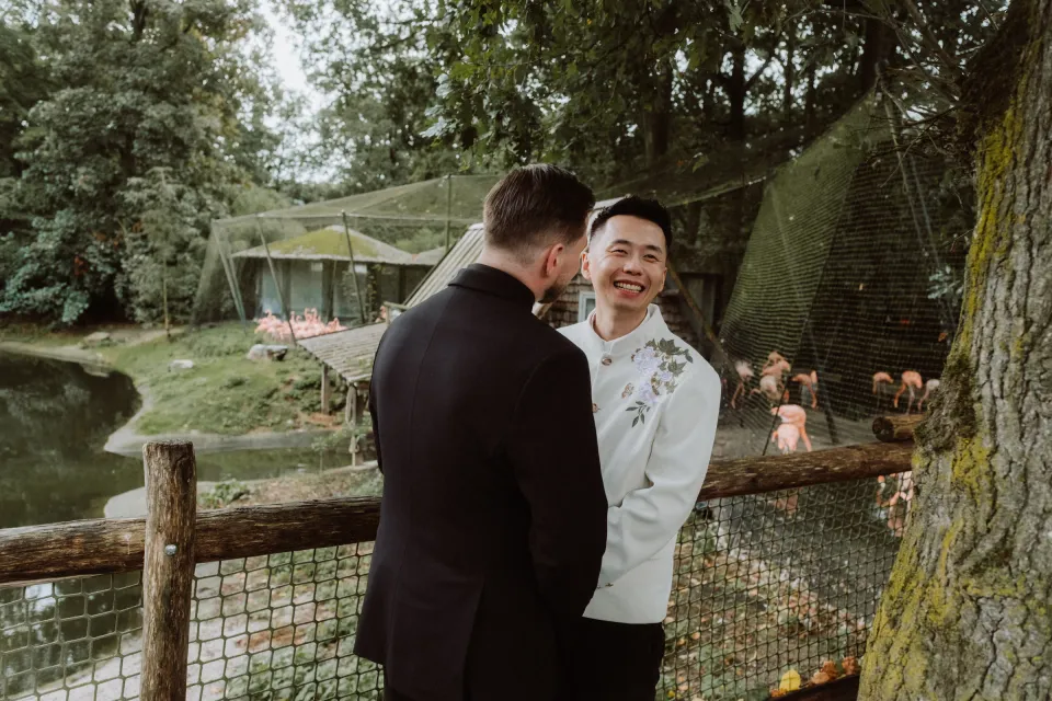 Kees looking at a smiling Ricky, with flamingos behind them.