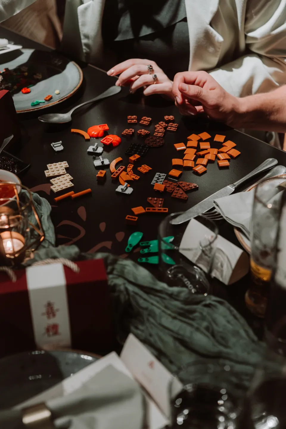 Guests’ hands sorting and building LEGO pieces at the dinner table.