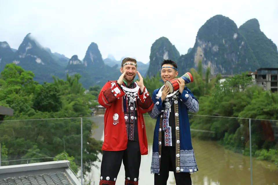 Ricky and Kees in traditional dress with a karst landscape behind them in China.